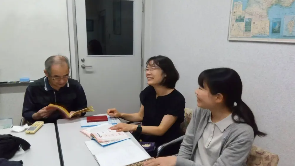 中国語の講師と生徒が少人数で会話練習をしている授業風景です。