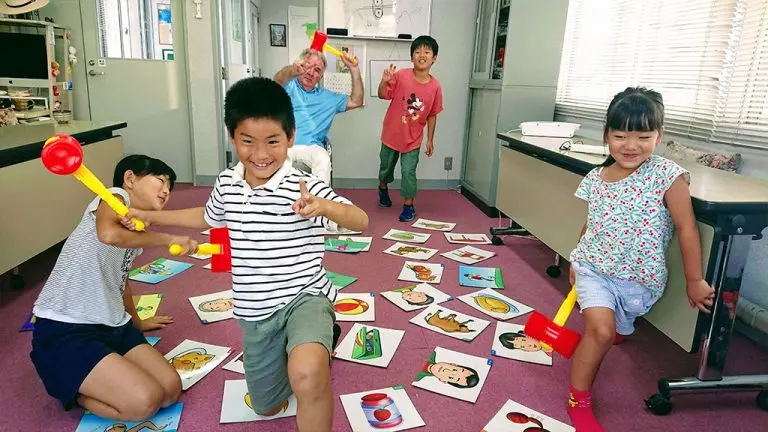 小学生が英語の教材を使って楽しく学んでいる授業の写真です。