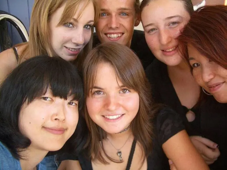 外国人の友人と一緒に笑顔で写っている生徒たちの写真です。語学を学ぶ楽しさを表しています。