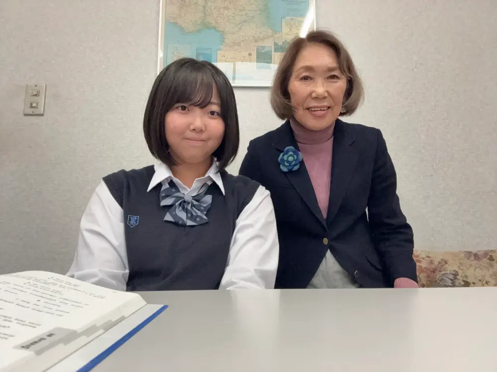 都志先生が生徒と並んで英語学習をサポートしている写真です。